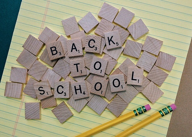 Scrabble tiles spelling out 'Back to School' laying on a yellow legal pad with two pencils below